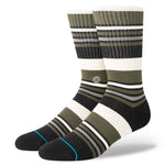 MOSSY CREW SOCK 2024 - Moss-colored crew socks with a repeating pattern of thin white stripes and a small logo on the ankle.
