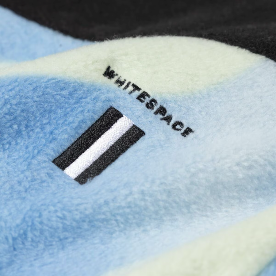 Whitespace Apres Polar Fleece Zip Jacket 2024 - A light blue fleece jacket with a white stripe on the left chest and black zipper.