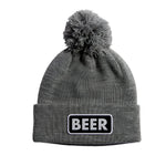 VICE POM BEANIE 2024 - A gray beanie with a large pom-pom on top.