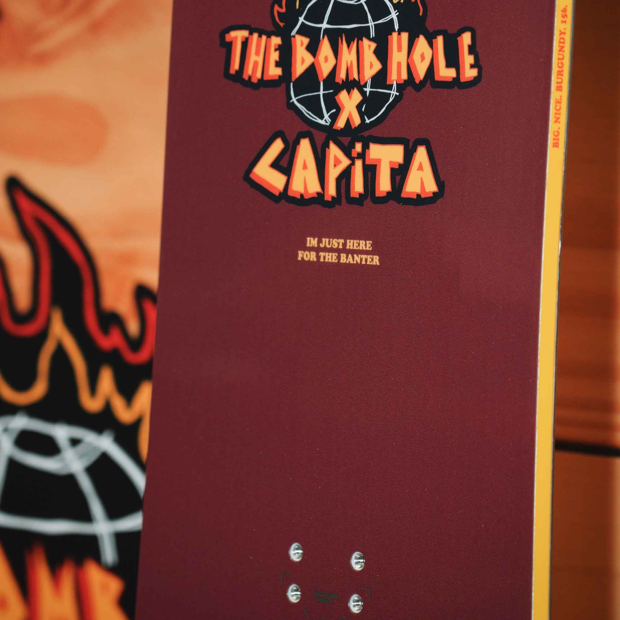 CAPITA Big Nice Burgundy Snowboard 2025 - A burgundy snowboard with a white logo and text on top of it.