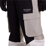 Whitespace 2L Cargo Insulated Bib Pants 2024 - Black bib pants with cargo pockets on each thigh and a white stripe down the side of one leg.