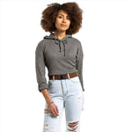 A person wearing the orange belt with a textured pattern. They are dressed in a casual outfit with a gray cropped sweater, distressed light blue jeans, and standing with a neutral expression.