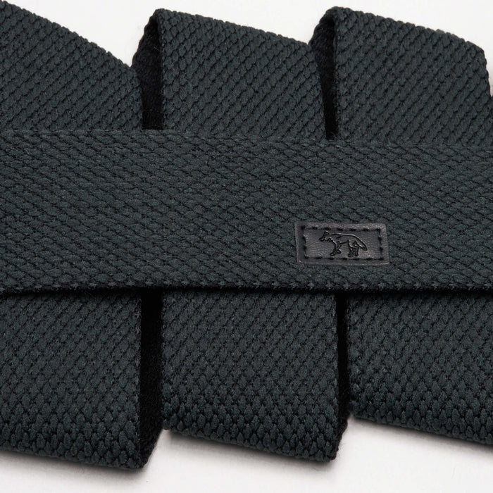 Close-up of the dark green belt showing the detailed textured pattern, along with the small leather patch with a coyote logo.