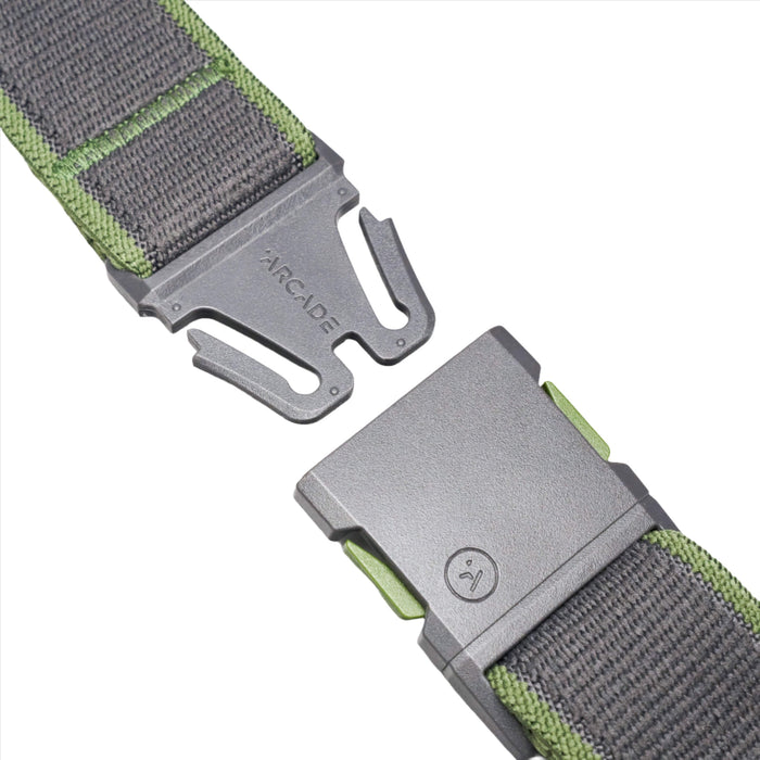 A close-up of a grey belt with green edges, showing a plastic buckle. The buckle is detached, revealing the word 'ARCADE' embossed on the male end and a small logo on the female end.