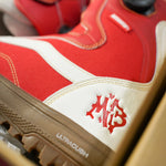 Vans Women's Encore Pro Limited Edition Snowboard Boots 2026 - A pair of red snowboard boots with white accents and a black strap on top.