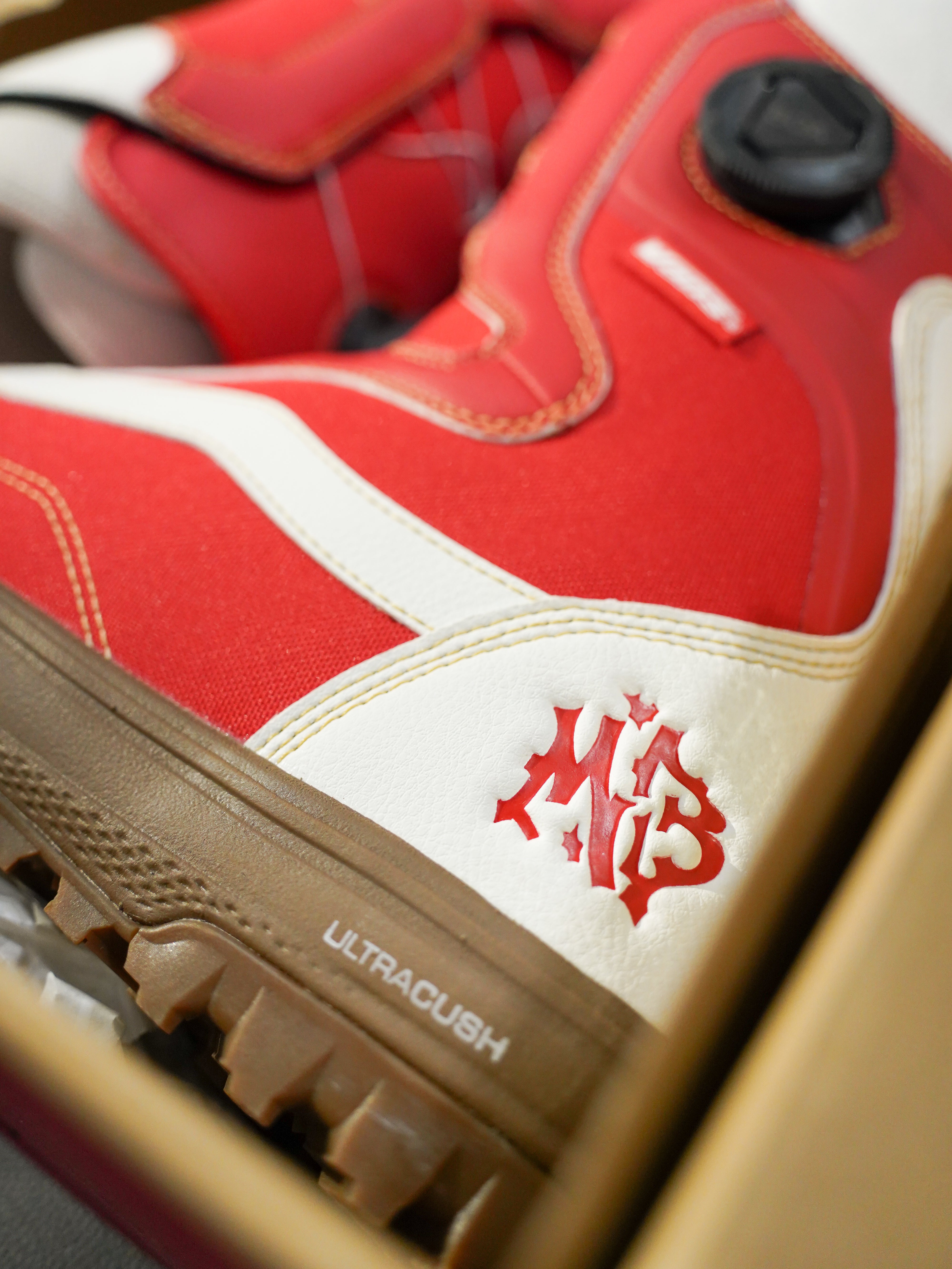 Vans Women's Encore Pro Limited Edition Snowboard Boots 2026 - A pair of red snowboard boots with white accents and a black strap on top.