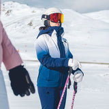 Descente Women's Swiss Insulated Jacket - A woman in a white and blue jacket with a hood, wearing a white helmet and red goggles, holding ski poles while standing on a snowy mountain.