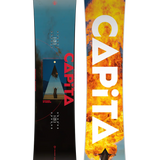 CAPiTA Defenders Of Awesome Snowboard 2025 - A blue and black snowboard with a triangular logo featuring a person standing in front of a mountain range, set against a dark background.