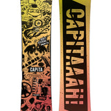 CAPiTA - Junior's Scott Stevens Mini Snowboard 2025 is a snowboard with a yellow background and black graphics of various shapes, including a smiling face, a fish, and a mountain peak.
