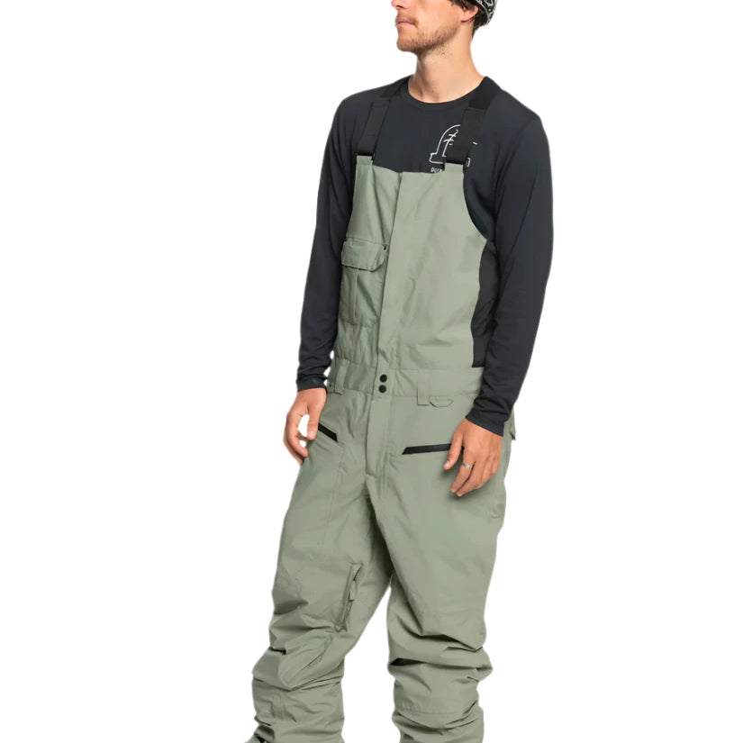 Quiksilver Utility Shell Bib - A pair of olive green snow pants with a zippered pocket on the thigh and adjustable Velcro straps at the waist.