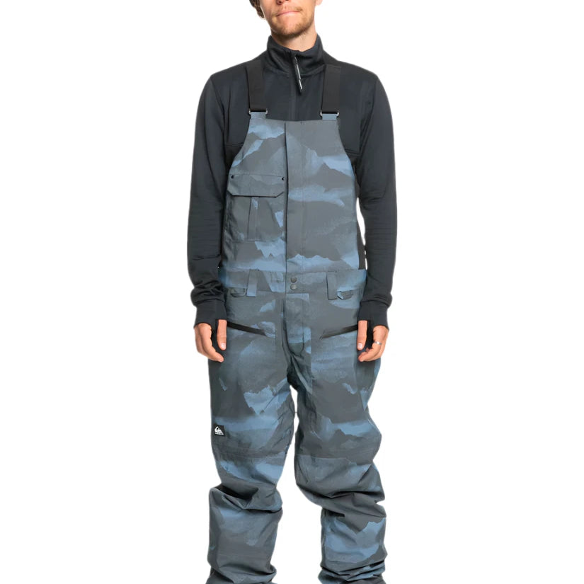 Quiksilver Utility Shell Bib - A pair of dark gray snow pants with a subtle black pattern and two zippered pockets on the side.