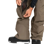 Quiksilver Utility Shell Pant 2025 - A pair of khaki-colored snow pants with a zippered pocket on the thigh and a black logo patch on the left leg.