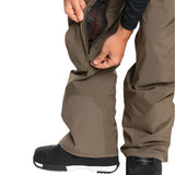 Quiksilver Utility Shell Pant 2025 - A pair of khaki-colored snow pants with a zippered pocket on the thigh and a black logo patch on the left leg.