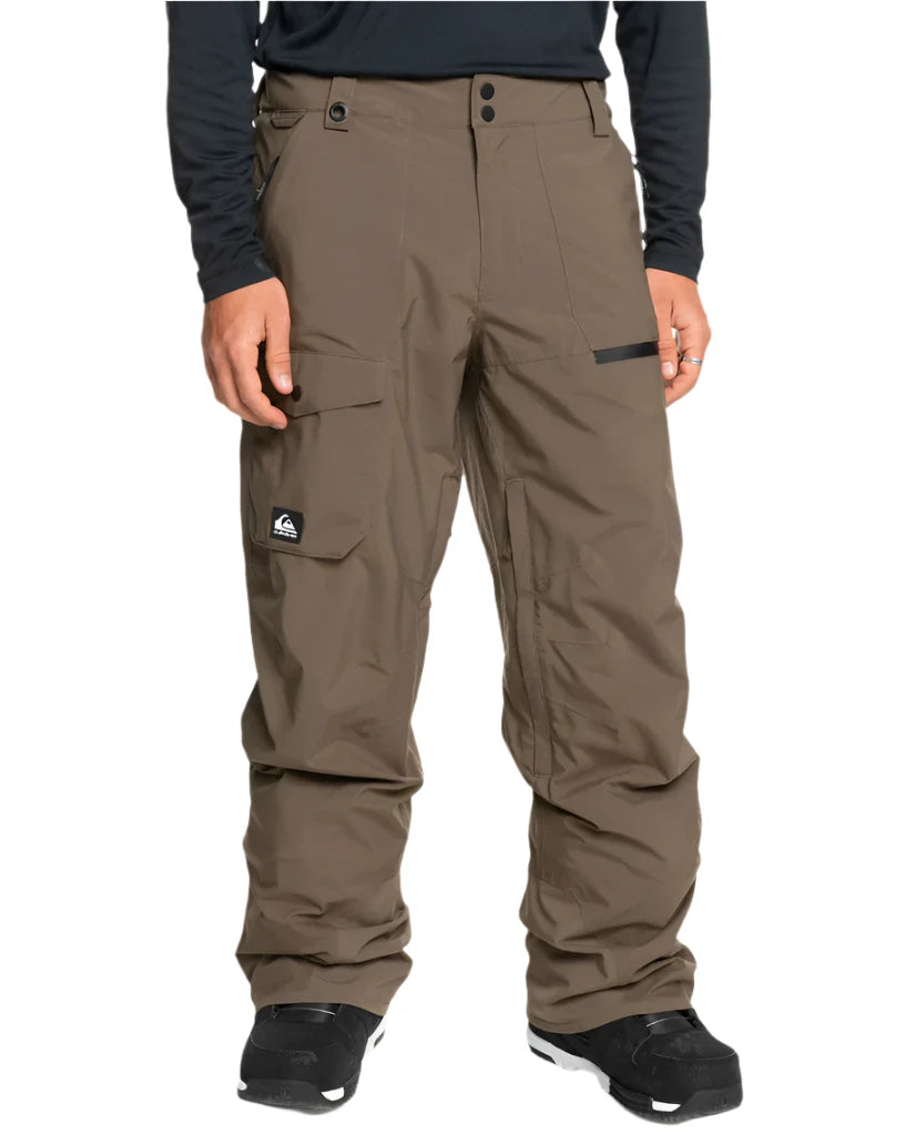 Quiksilver Utility Shell Pant 2025 - A pair of khaki-colored snow pants with a black logo patch on the left thigh and two zippered pockets on the right leg.