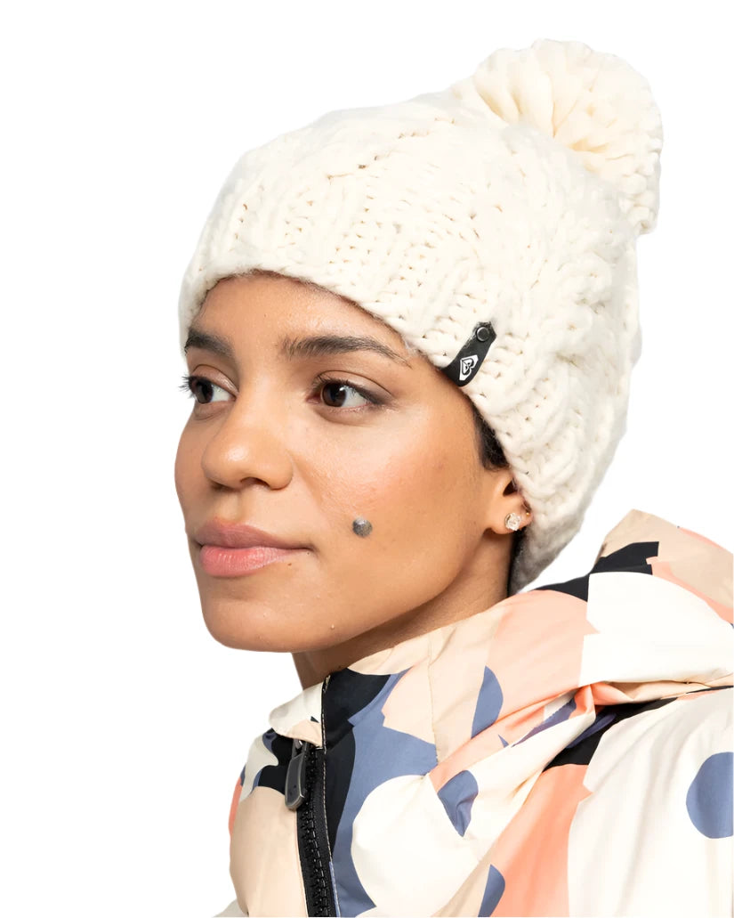 Roxy Women's Winter Beanie 2025 - A cream-colored beanie with a black tag on the side featuring a white logo.