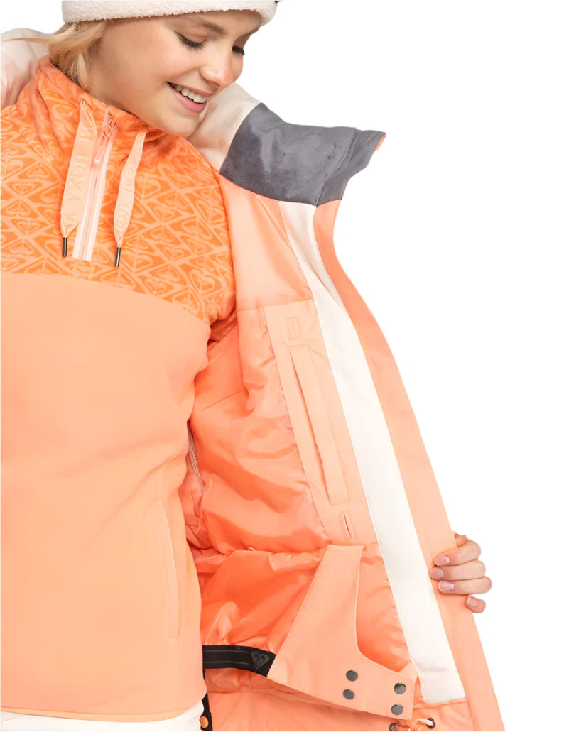 Roxy Women's Meade Insulated Jacket - A peach-colored jacket with a geometric pattern on the upper chest area, featuring a zippered pocket and adjustable cuffs.