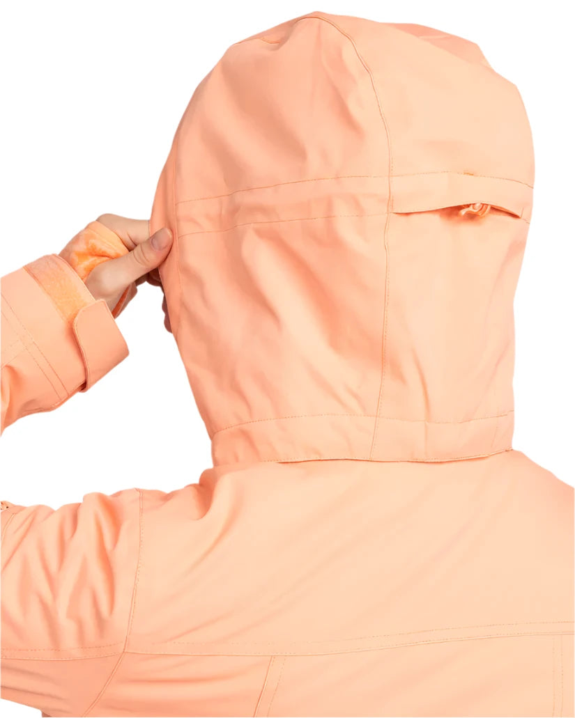 Roxy Women's Meade Insulated Jacket - A woman wearing a peach-colored jacket with a hood, holding it up to show off its design.