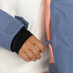 Roxy Women's Shelter Insulated Jacket - A woman's hand is adjusting a zipper on the sleeve of this blue jacket with black cuffs and a pink lining visible inside.