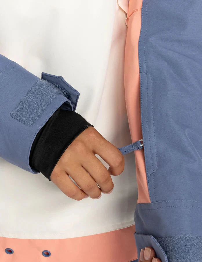 Roxy Women's Shelter Insulated Jacket - A woman's hand is adjusting a zipper on the sleeve of this blue jacket with black cuffs and a pink lining visible inside.