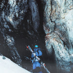 A skier wearing a blue jacket and black pants, standing on snowy mountain with Salomon S/Lab QST Blank Skis 2026.