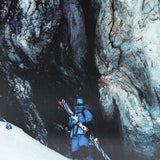 A skier wearing a blue jacket and black pants, standing on snowy mountain with Salomon S/Lab QST Blank Skis 2026.