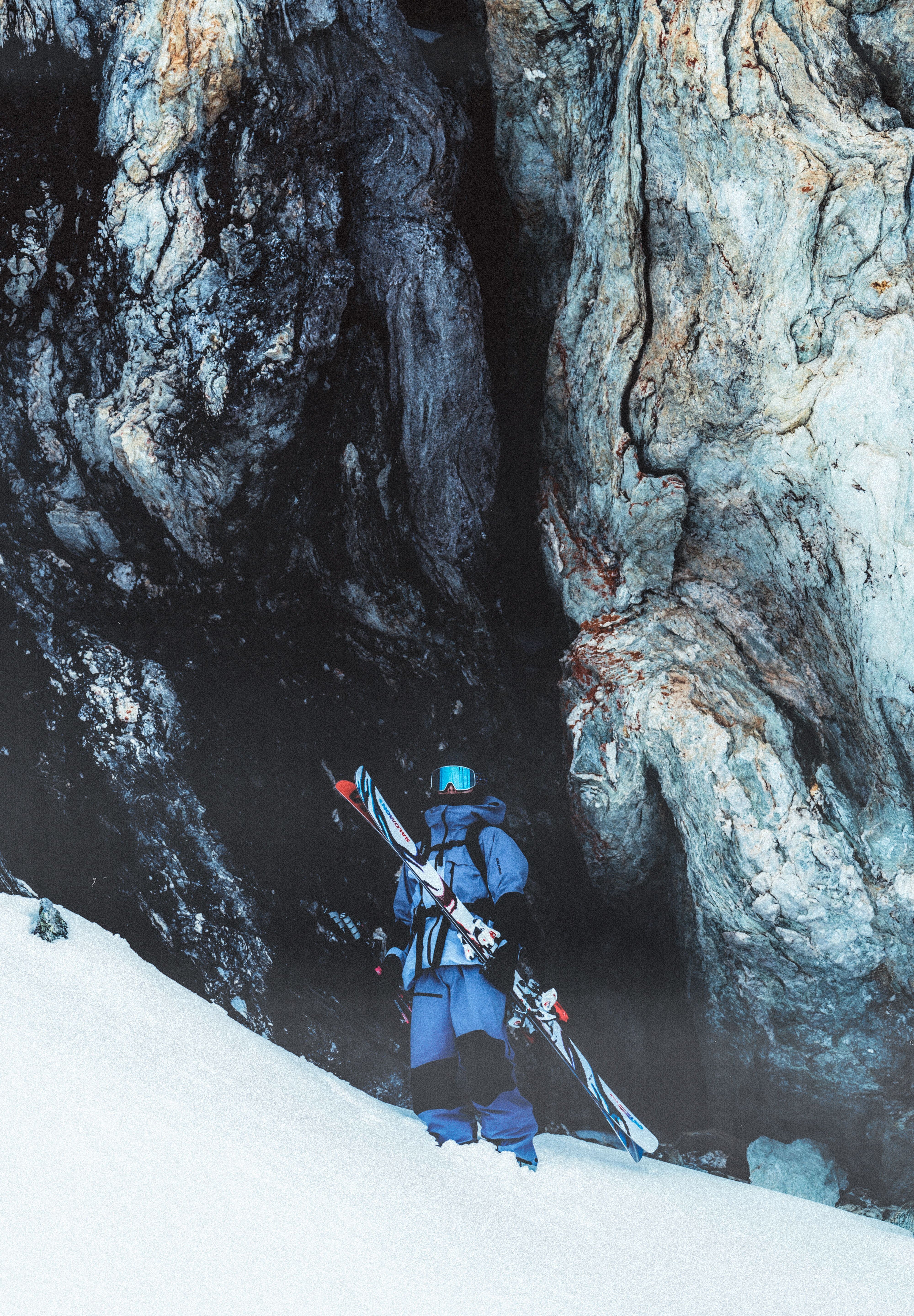 A skier wearing a blue jacket and black pants, standing on snowy mountain with Salomon S/Lab QST Blank Skis 2026.