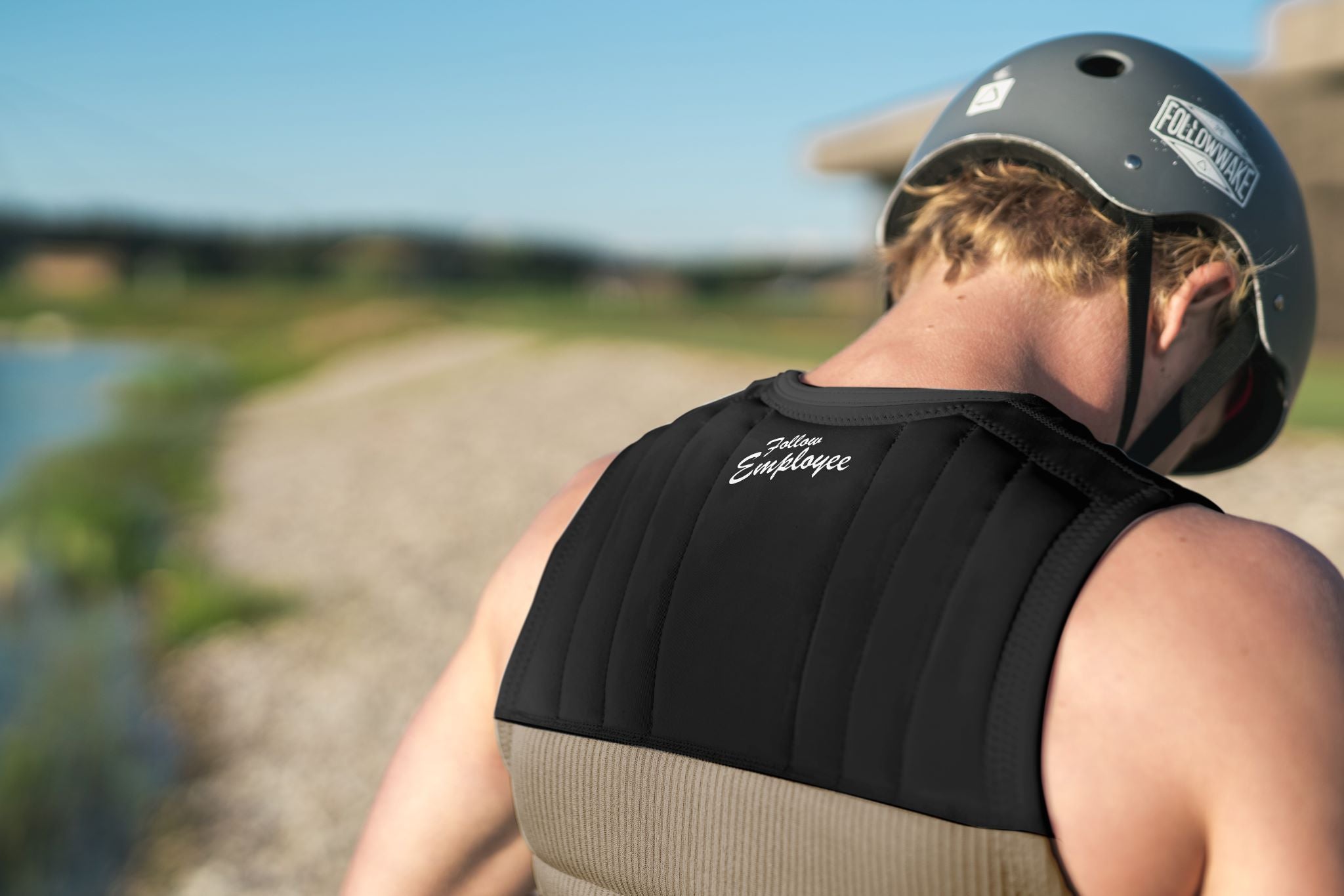 Follow Employee Of The Month Impact Vest 2024 - A black vest with white lettering and a logo on the back.