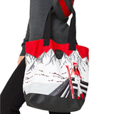 Krimson Klover Women's Illustrated Tote 2025 - A gray tote with a red and black illustration of skiers on the front.