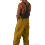 Flylow Firebird Bib - A pair of brown snow pants with a black logo on the left leg and a zippered pocket on the right thigh.