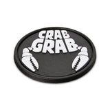 Crab Grab The Logo Stomp Pad 2025 - A black oval-shaped pad with a raised white logo featuring the words "CRAB GRAB" in bold block letters, flanked by two crab claws on either side.
