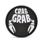 Crab Grab The Logo Stomp Pad 2025 - A round black pad with a white logo featuring the words "CRAB GRAB" in bold block letters, surrounded by two crab claws.