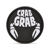Crab Grab The Logo Stomp Pad 2025 - A round black pad with a white logo featuring the words "CRAB GRAB" in bold block letters, surrounded by two crab claws.