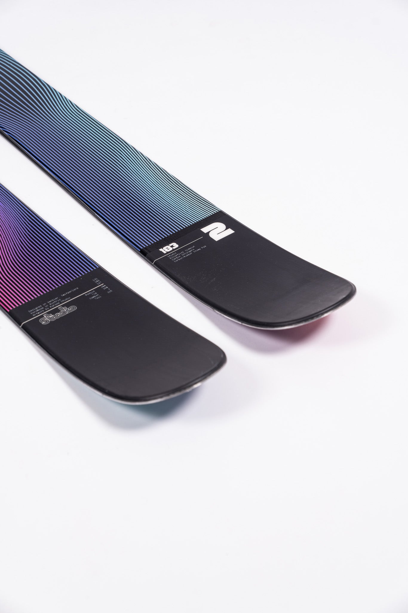 Faction Studio 2 Ski 2025 - A pair of skis with a black base and blue, purple, and pink gradient stripes on top.