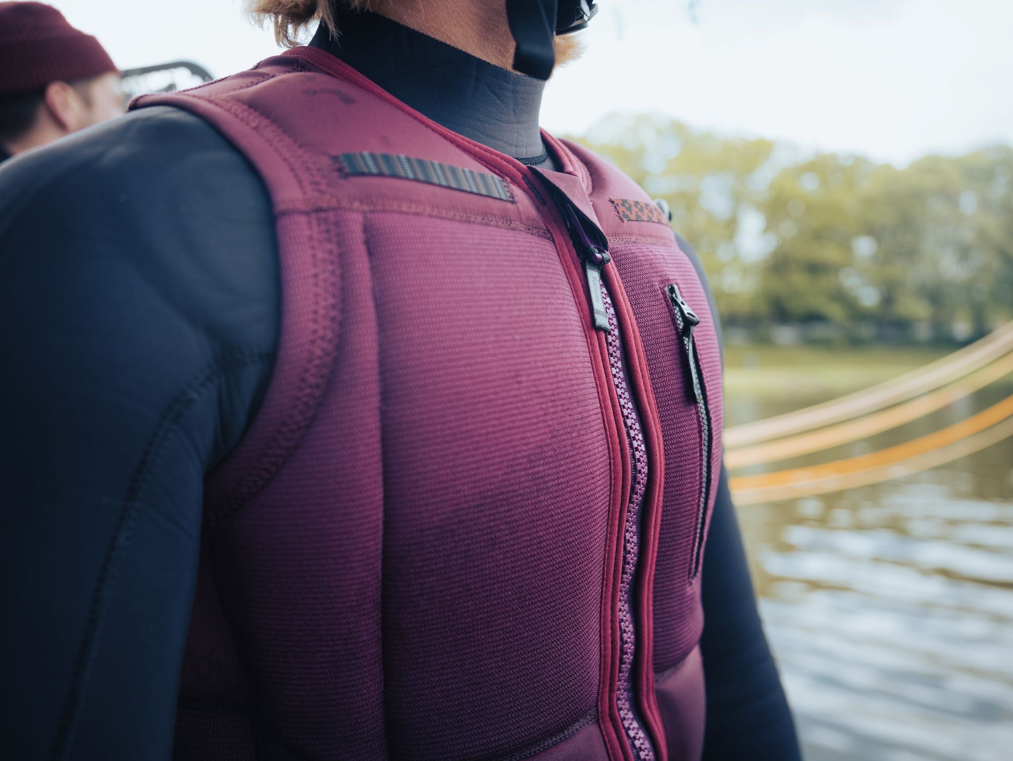 Follow Capiva Impact Vest 2024 - A red impact vest with a black logo on the upper left side and a black strap at the back.