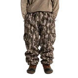 Camouflage cargo shell pants worn, with an elastic waist and flap thigh pockets
