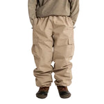 Stone cargo shell pants worn, with an elastic waist and flap thigh pockets