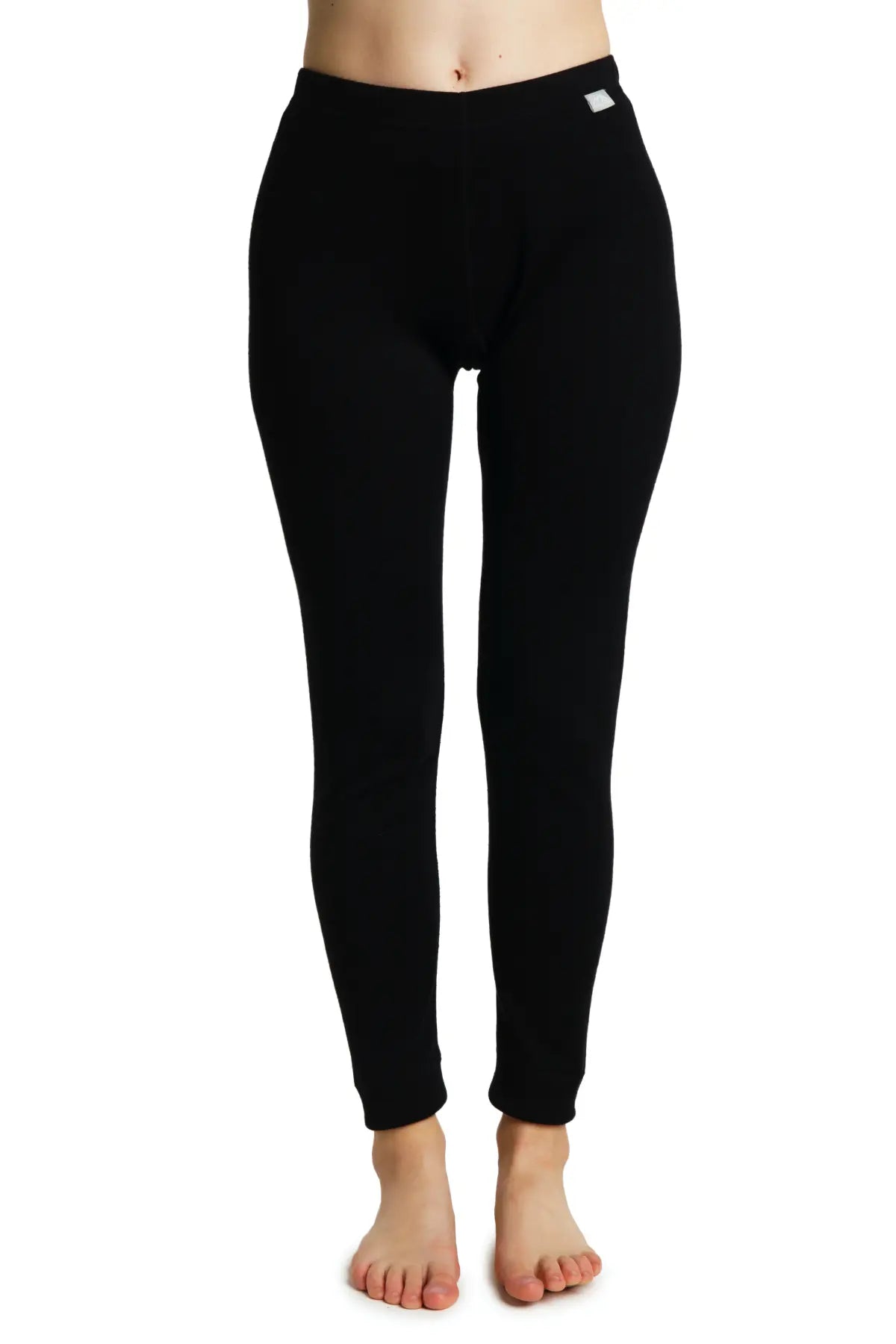 Treviso Women's Merino Pants - A pair of black merino wool pants with a white tag on the right side, worn by a model without shoes or socks.