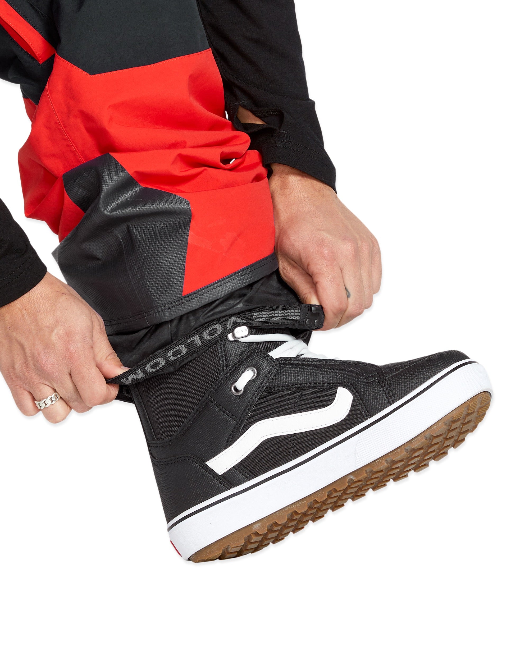 Volcom Men's Rain GORE-TEX Bib Overall - A pair of black rain pants with a red stripe down the side, featuring a zipper and button fly closure.