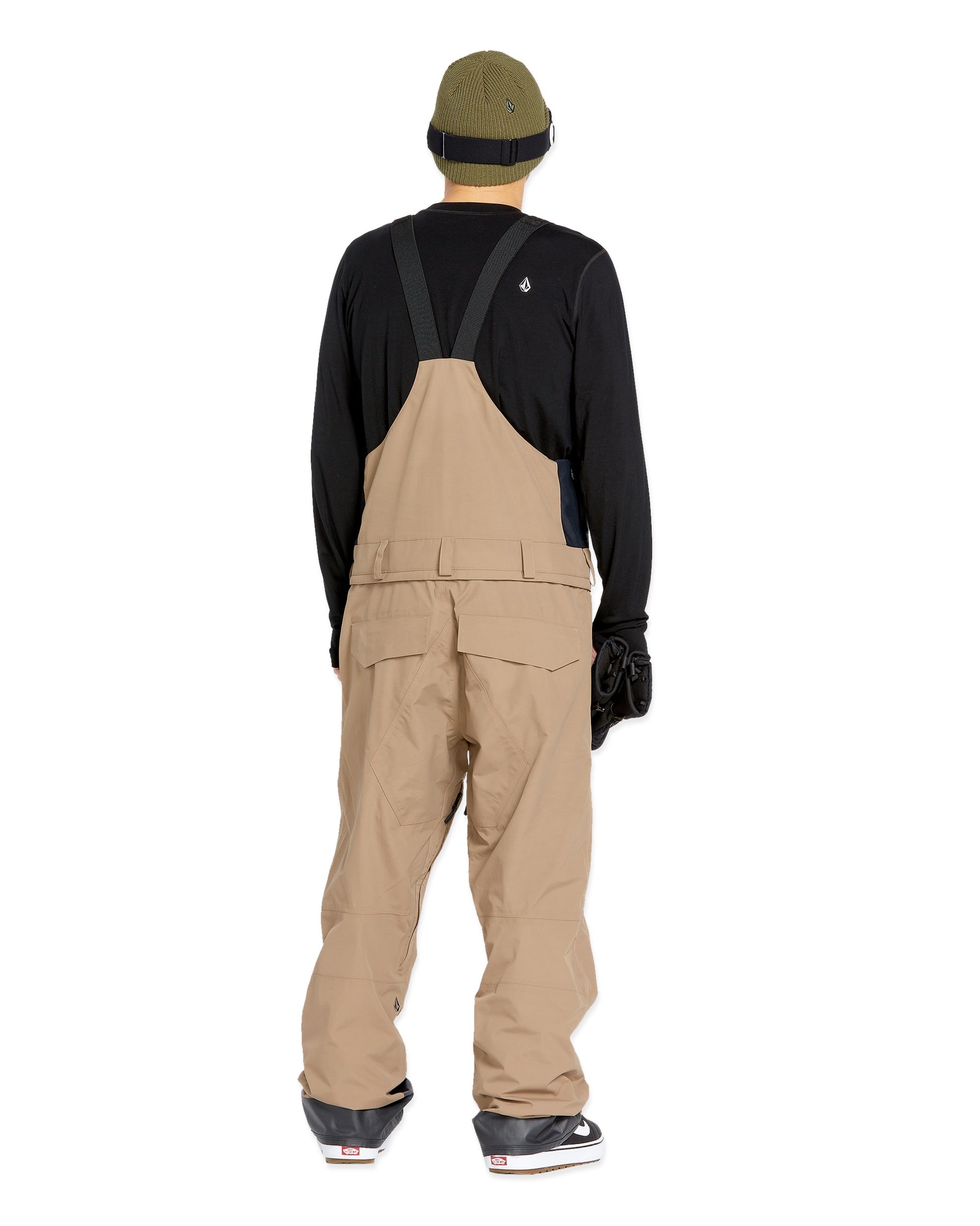 Volcom Men's Rain GORE-TEX Bib Overall - A pair of khaki-colored bib overalls with a black strap and buckle at the back, featuring two front pockets and a zippered pocket on the thigh.