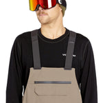 Volcom Men's Rain GORE-TEX Bib Overall - A pair of khaki-colored bib overalls with a zippered front pocket and adjustable straps.