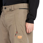 Volcom Men's Longo GORE-TEX Shell Pants - A pair of khaki-colored pants with a zippered pocket on the thigh and a black zipper pull.