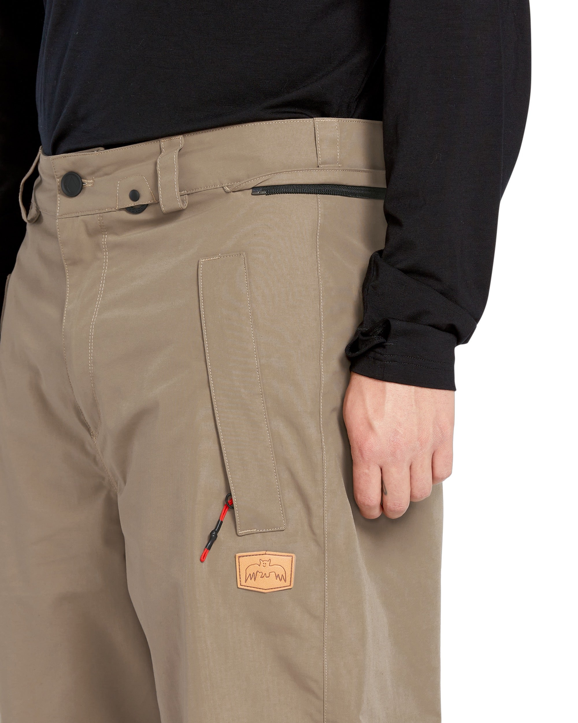 Volcom Men's Longo GORE-TEX Shell Pants - A pair of khaki-colored pants with a zippered pocket on the thigh and a black zipper pull.