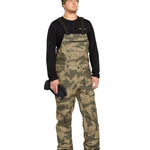Volcom Men's Roan Shell Bib Overall - A pair of khaki-colored snow bib overalls with a subtle pattern and multiple pockets.