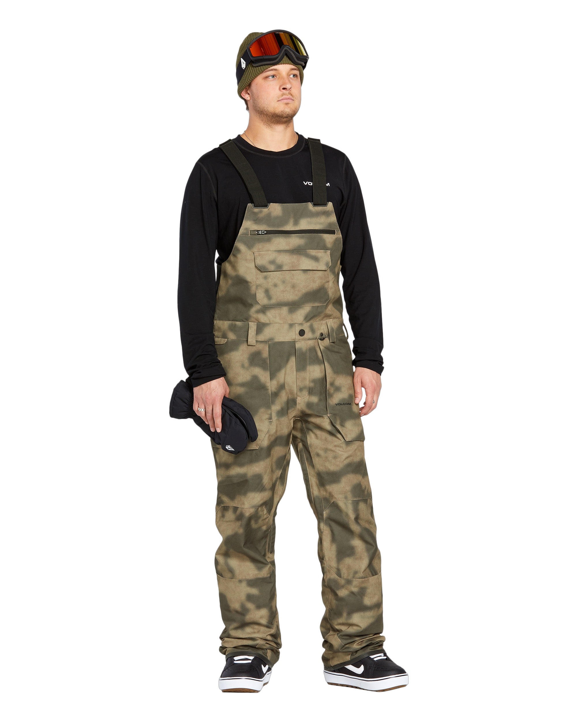 Volcom Men's Roan Shell Bib Overall - A pair of khaki-colored snow bib overalls with a subtle pattern and multiple pockets.