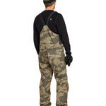 Volcom Men's Roan Shell Bib Overall - A pair of khaki-colored snow bib overalls with a subtle camouflage pattern, featuring adjustable straps and multiple pockets.