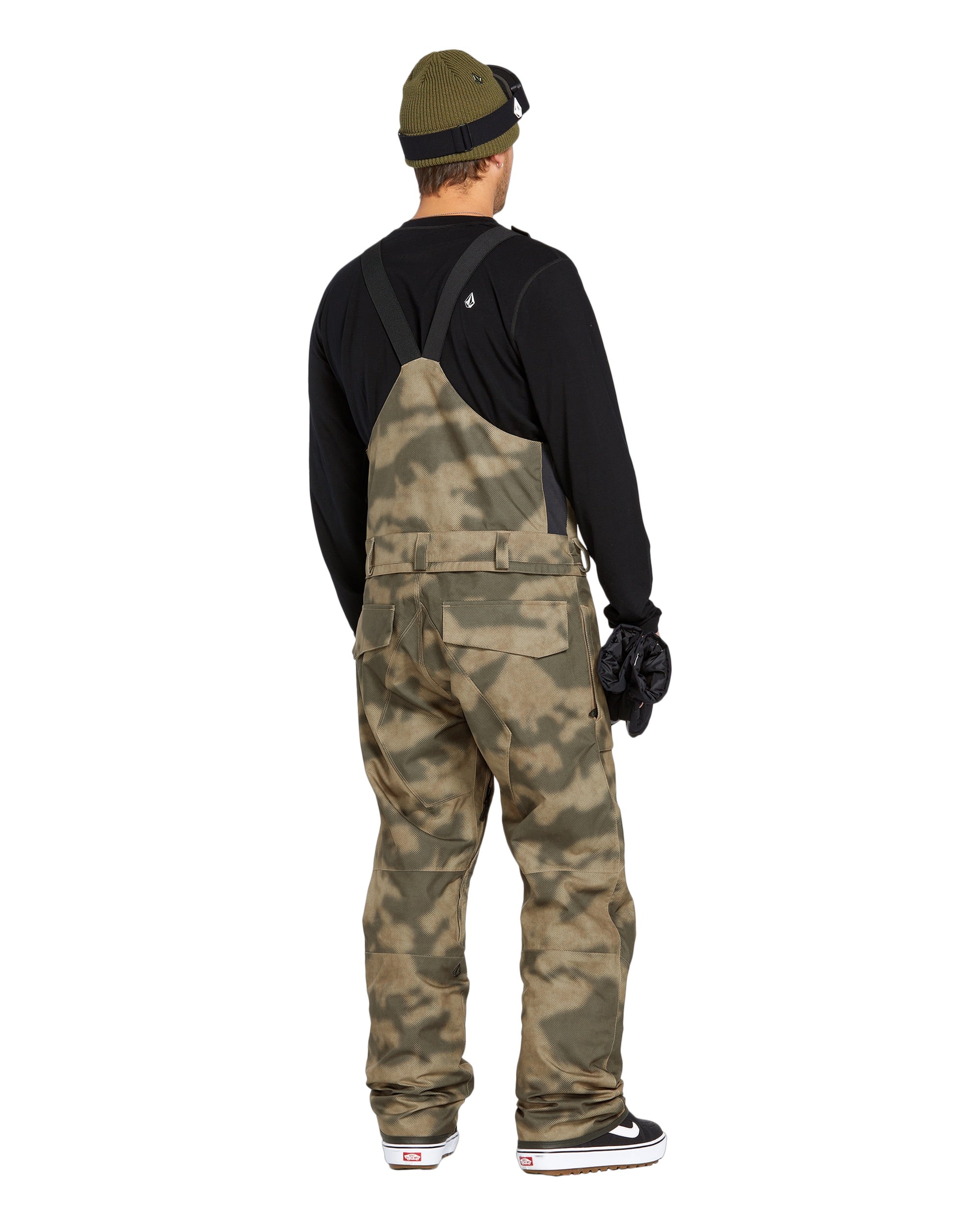 Volcom Men's Roan Shell Bib Overall - A pair of khaki-colored snow bib overalls with a subtle camouflage pattern, featuring adjustable straps and multiple pockets.