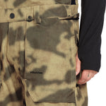Volcom Men's Roan Shell Bib Overall - A camouflage-patterned overall with a black belt and two front pockets.