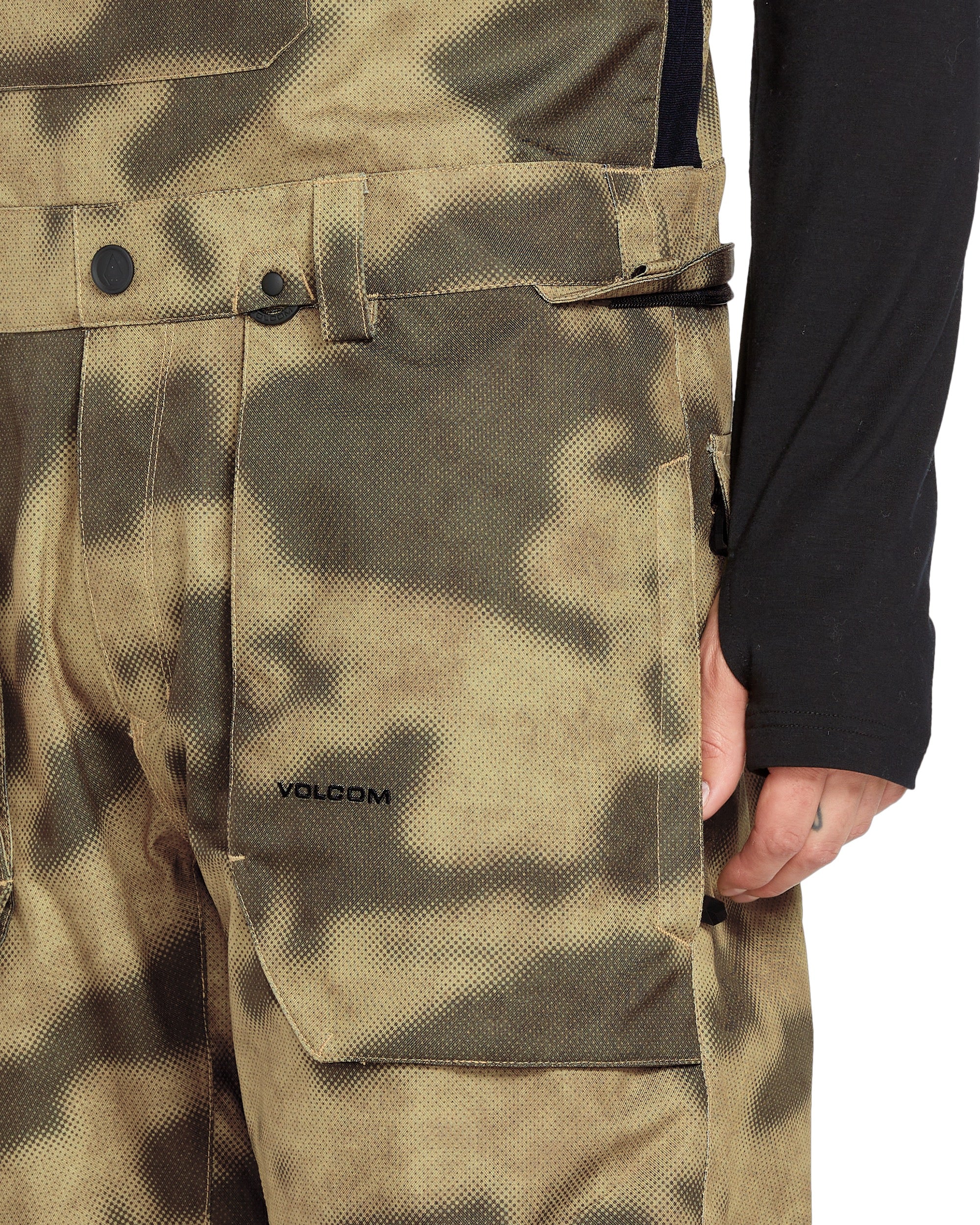 Volcom Men's Roan Shell Bib Overall - A camouflage-patterned overall with a black belt and two front pockets.