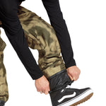 Volcom Men's Roan Shell Bib Overall - A pair of khaki-colored snow pants with a subtle pattern and zippered pockets.