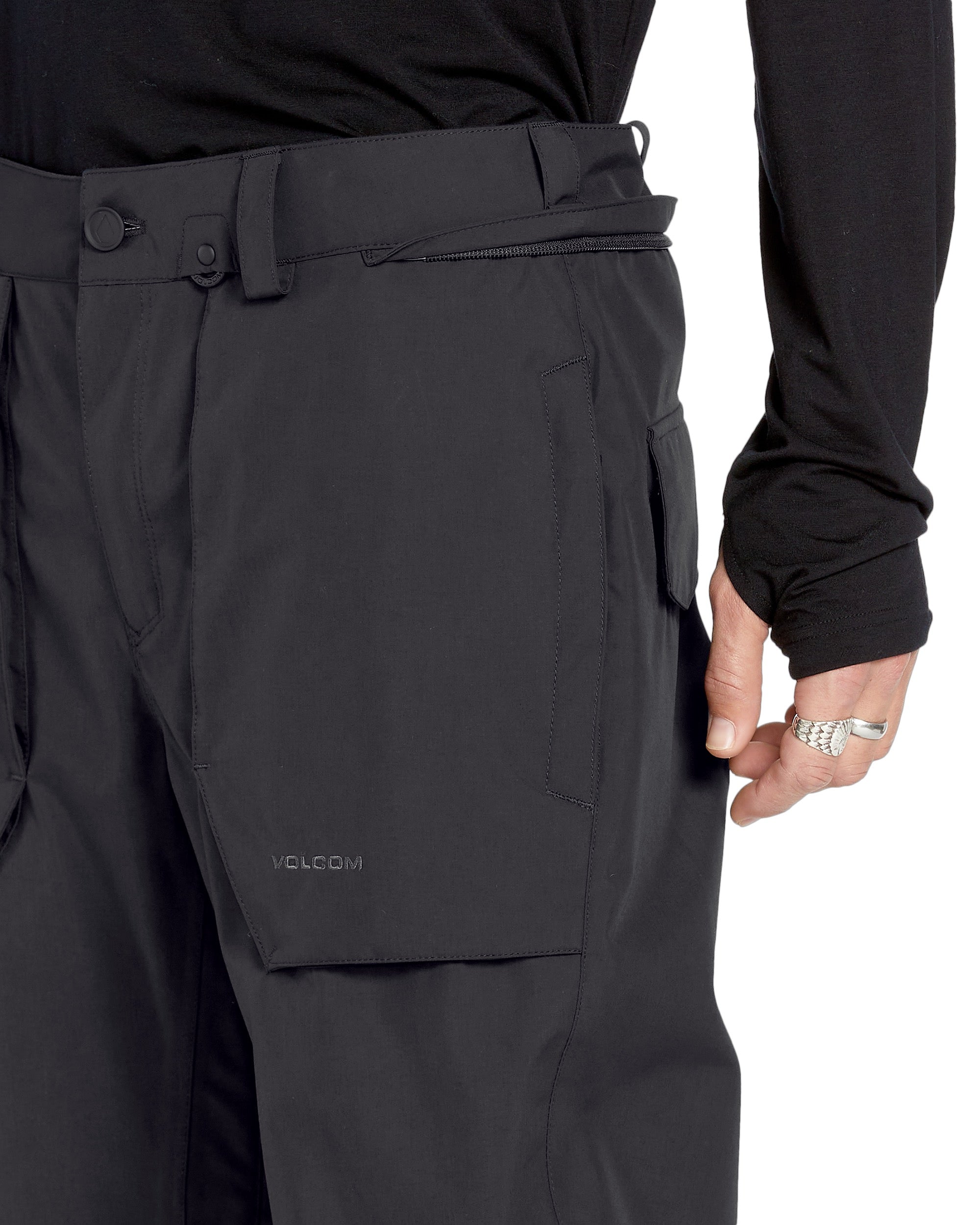 Volcom Men's Roan Shell Pant - A pair of black snow pants with a zippered pocket on the thigh and adjustable Velcro straps at the waist.